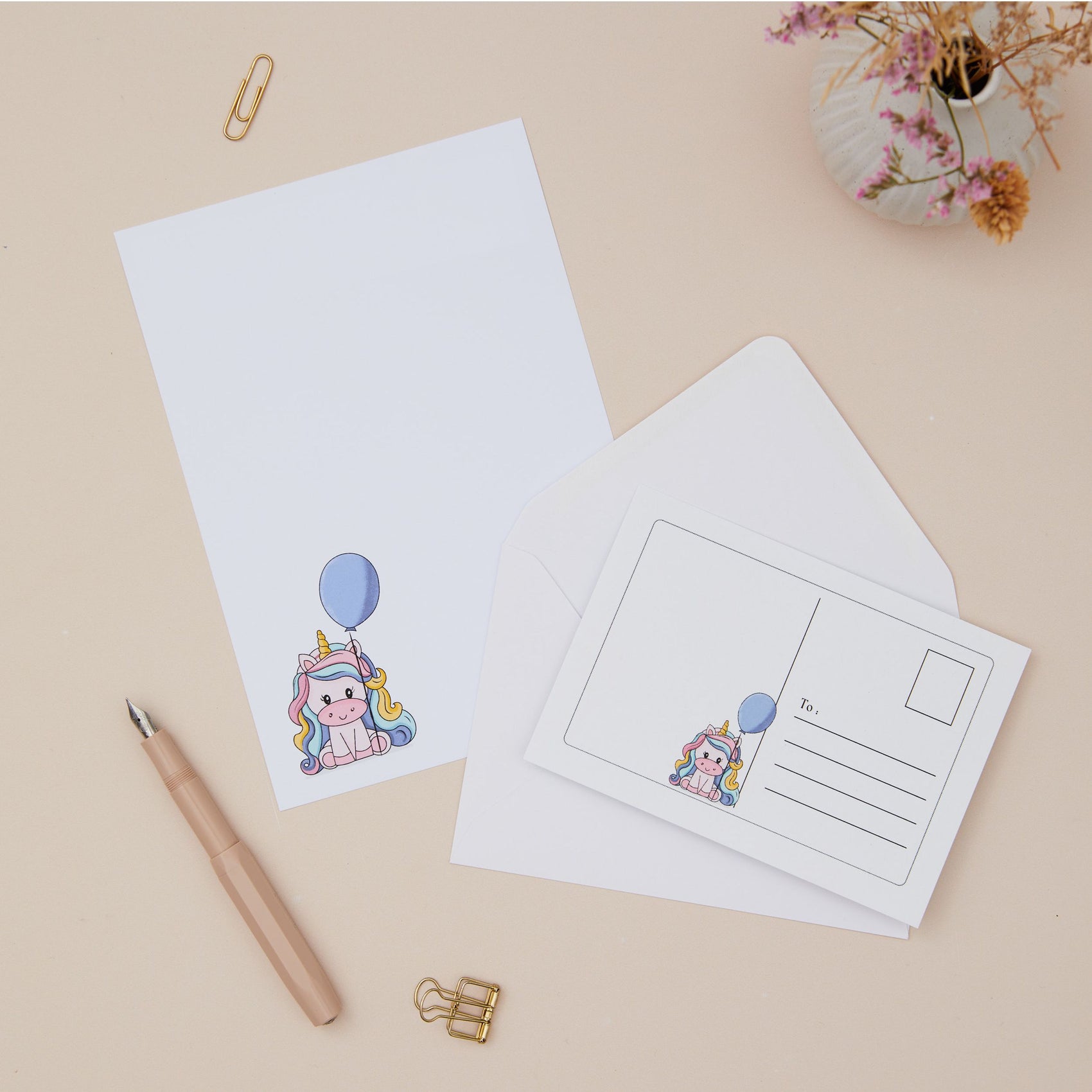 Unicorn Letter Writing Set and Postcards. The set is on a beige surface with stationery items.